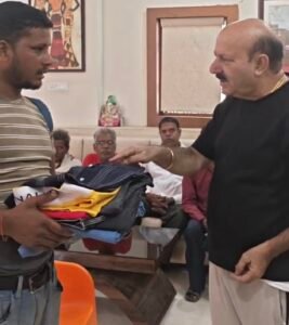 जरूरतमंद धर्मेंद्र निषाद को कपड़े देते पलिया विधायक रोमी साहनी